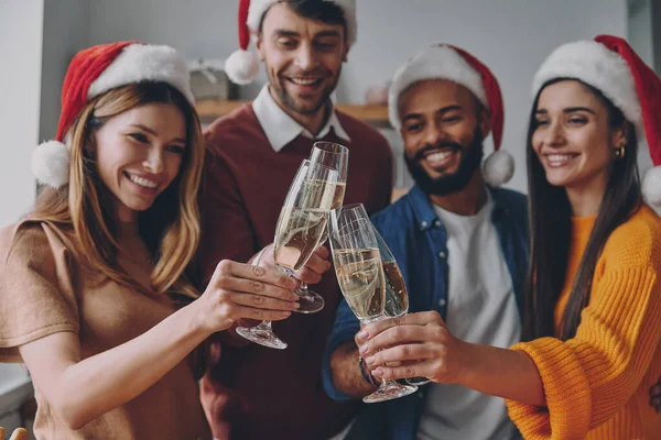 一群戴着圣诞礼帽 戴着香槟酒 面带微笑的漂亮年轻人 — 图库照片