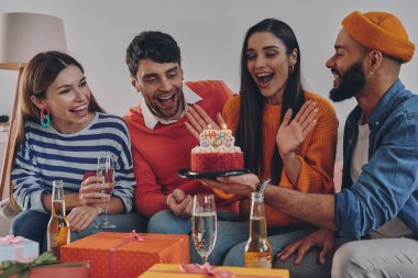 Güzel genç insanlar evde kutlama yaparken arkadaşını doğum günüyle kutluyorlar.