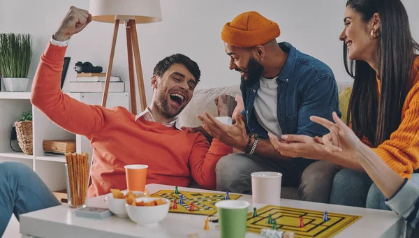 Beautiful young people playing board game while enjoying carefree time together