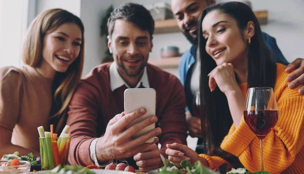 Grupo Jovens Felizes Olhando Para Telefone Inteligente Enquanto Desfrutam Jantar — Fotografia de Stock