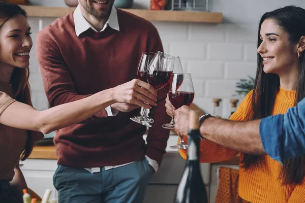 Beautiful young people toasting with wine while spending time at home together
