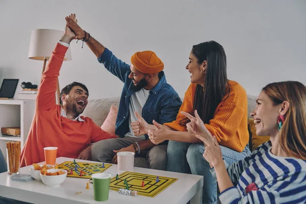 Happy young people playing board game while enjoying carefree time together