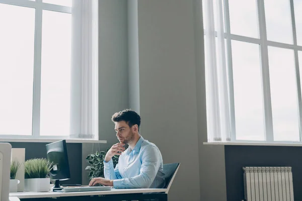 オフィスの彼の職場に座っている間 コンピュータを使用して若いビジネスマンを自信を持って — ストック写真