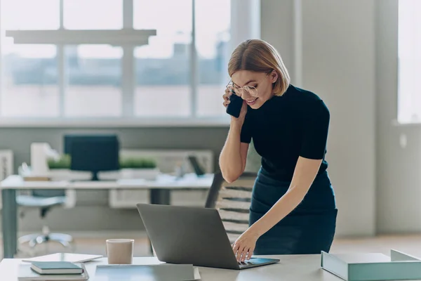 Ofiste Çalışırken Cep Telefonuyla Konuşan Genç Mutlu Bir Kadını — Stok fotoğraf