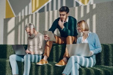 Birlikte yaratıcı alanda çalışırken teknolojileri kullanan kendine güvenen iş adamları.