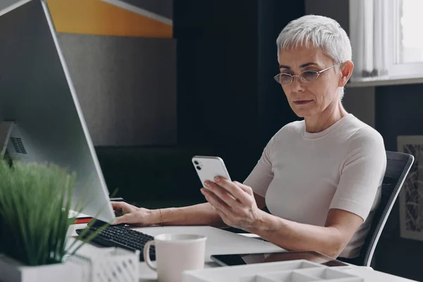 Confident Senior Businesswoman Using Smart Phone While Sitting Her Working — Stock Photo, Image