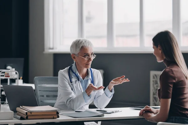 Dokter Wanita Senior Berbicara Dengan Pasien Dan Memberi Isyarat Saat — Stok Foto