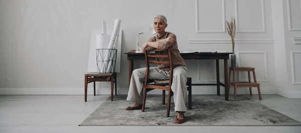 Yaratıcı Çalışma Yerinde Otururken Kameraya Bakan Kendinden Emin Yaşlı Kadın — Stok fotoğraf