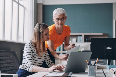 Ofiste çalışırken iş hakkında konuşan iki kendine güvenen kadın.