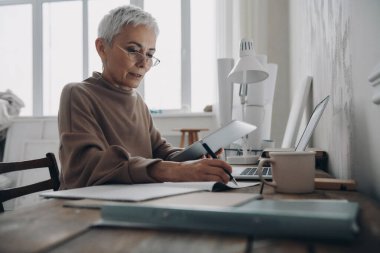 Ofisteki masada otururken not alan son sınıf öğrencisi bir kadın.