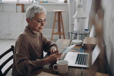 İş yerinde otururken dijital tablet kullanan kendinden emin bir iş kadını.