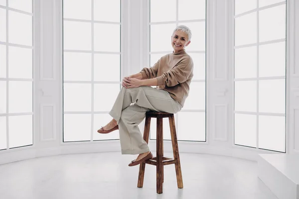Felice Donna Anziana Guardando Fotocamera Mentre Seduto Sulla Sedia Contro — Foto Stock