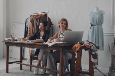 İki kendine güvenen moda tasarımcısı birlikte atölyede yeni bir koleksiyon üzerinde çalışıyorlar.