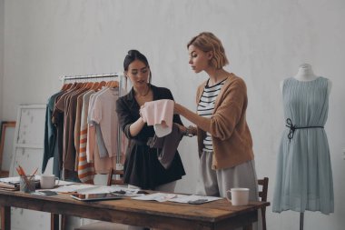 İki kendine güvenen moda tasarımcısı atölyede yeni koleksiyon için tekstil seçiyor.