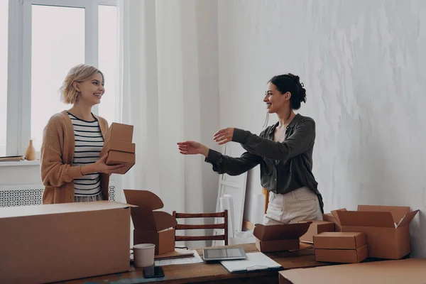 Two happy female business partners preparing packages for delivery in warehouse
