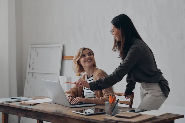 2人の幸せな若い女性が創造的なオフィスで一緒に仕事をしながらビジネスを議論する — ストック写真