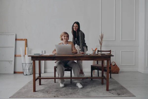 Två Glada Unga Affärskvinnor Som Använder Laptop Samtidigt Som Arbetar — Stockfoto