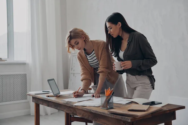 2人の若い女性の同僚が事務所で一緒に書類を扱う — ストック写真