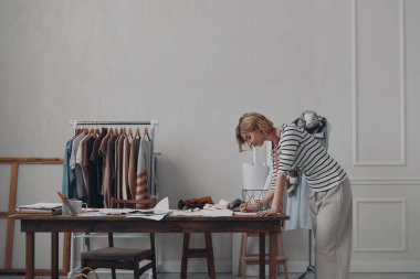 Kendine güvenen kadın moda tasarımcısı iş yerinin yanında dururken çizimler yapıyor.