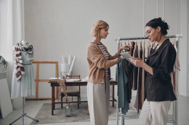 İki kendine güvenen moda tasarımcısı atölyede birlikte çalışıyor.