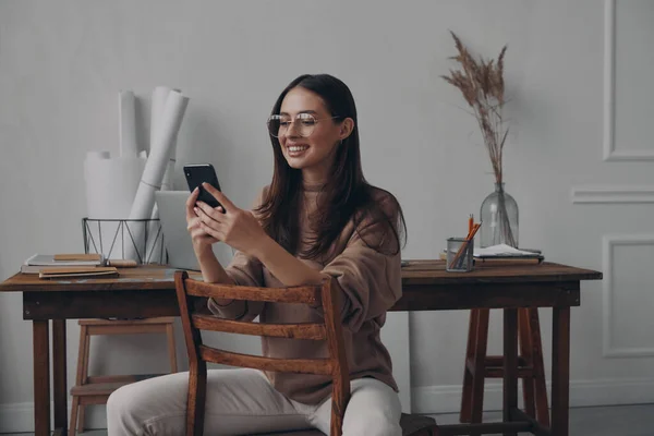 Щаслива Молода Жінка Використовує Смартфон Сидячи Своєму Робочому Місці Офісі — стокове фото