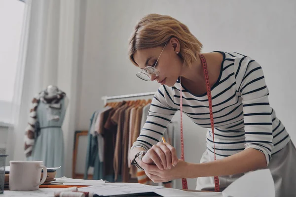 Upptagen Kvinnlig Modedesigner Kontrollerar Tiden Medan Planerar Kollektion Verkstad — Stockfoto