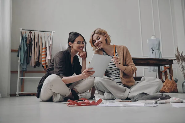 Dwie Szczęśliwe Projektantki Mody Pomocą Tabletu Cyfrowego Podczas Pracy Warsztacie — Zdjęcie stockowe
