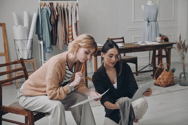 Två Självsäkra Kvinnliga Modedesigner Undersöker Skisser Medan Arbetar Verkstad — Stockfoto
