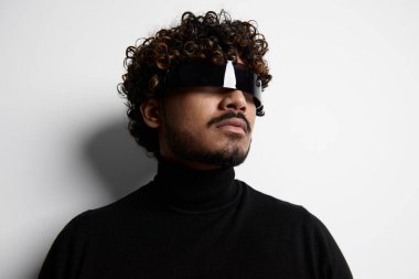 Arka planda dururken fütürist gözlük takan kendine güvenen Hintli.