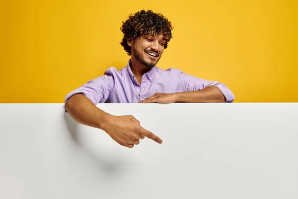 ハンサムな若いインド人男性を指してコピースペースと笑顔に対して黄色の背景 — ストック写真