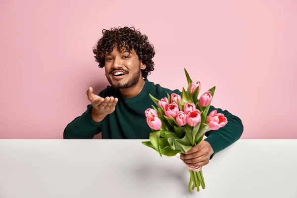 ハンサムなインド人男吹いてキスしながら保持花花束に対してピンクの背景 — ストック写真