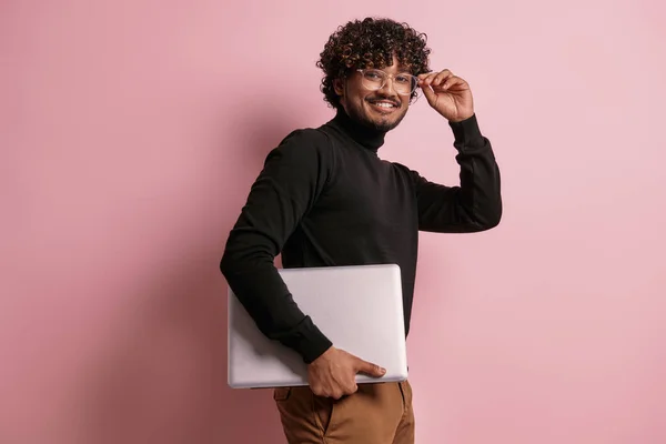 快乐的印度人 背着笔记本电脑 在粉色背景下调整眼镜 — 图库照片