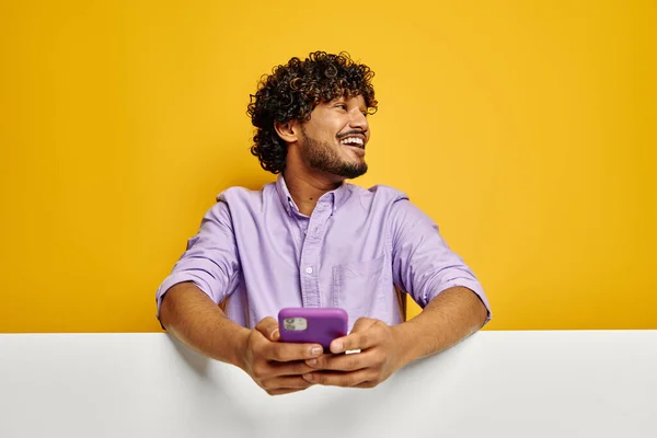 快乐的印度人靠在复制空间上 拿着黄色背景的智能手机 — 图库照片