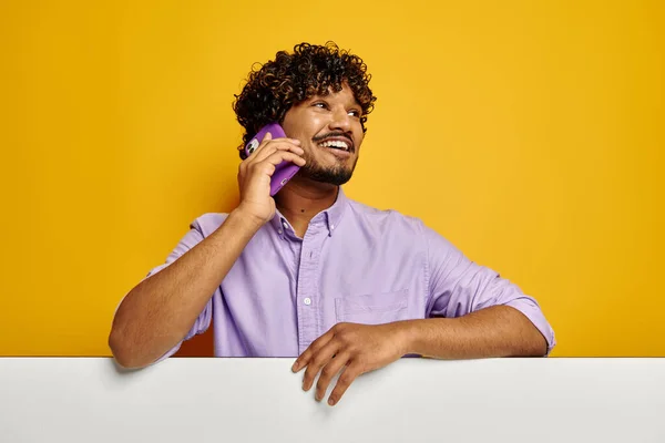 快乐的印度人靠在复制空间上 在黄色背景下通过电话交谈 — 图库照片