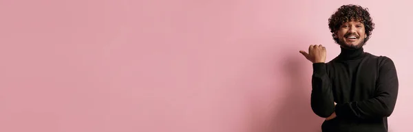 ハンサムなインド人男性ポインティングコピースペースと笑顔に対してピンクの背景 — ストック写真