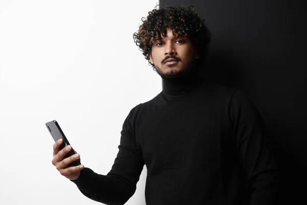 在黑白背景下拿着智能手机的英俊印度男人 — 图库照片