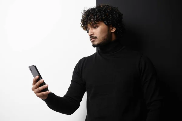 黒と白の背景に立っている間 スマートフォンを使用してハンサムなインド人男性 — ストック写真