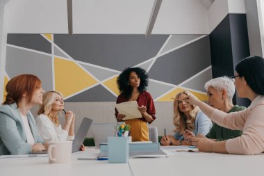 Bir grup kendinden emin iş kadını ofiste personel toplantısı yapıyor.