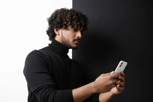 黒と白の背景に立っている間 スマートフォンを使用してインドの男を自信を持って — ストック写真