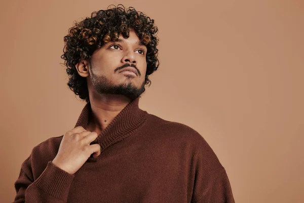 Stilvoller Indischer Mann Dehnt Pullover Kragen Während Vor Braunem Hintergrund — Stockfoto