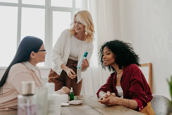 Three Happy Mature Women Examining Beauty Products While Sitting Desk — Stock Photo, Image