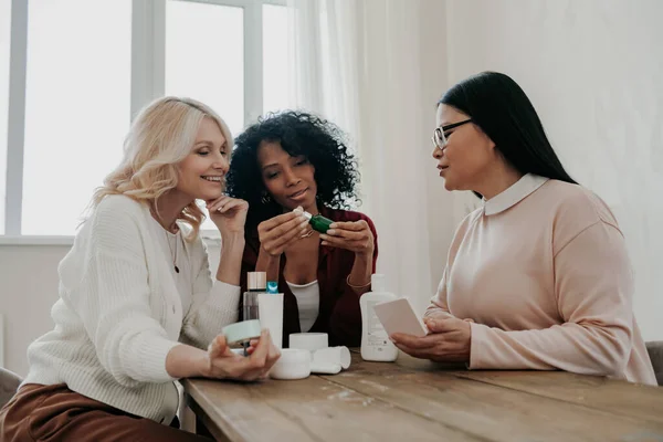 Tři Dospělé Ženy Diskutovat Kosmetických Procedur Zatímco Sedí Stolem Spolu — Stock fotografie