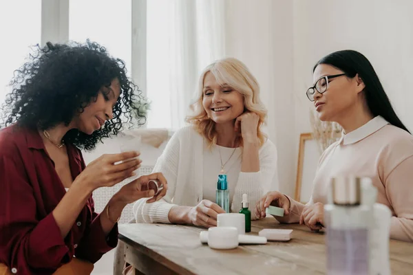 Three Mature Women Examining Beauty Products While Sitting Desk Together — Stock Photo, Image
