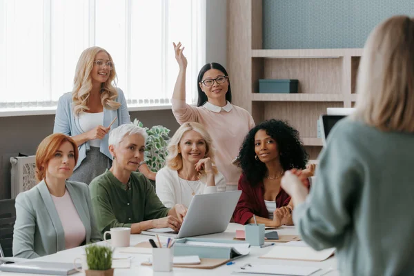 Stock image Group of mature women listening to speaker while having business training in office