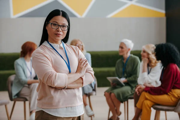 Confident Asian woman looking at camera while visiting group training class for females