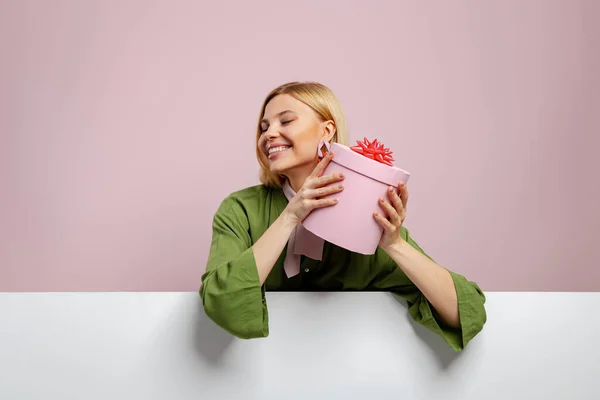 Привлекательная Молодая Женщина Держит Подарочную Коробку Возле Лица Улыбается Розовом — стоковое фото