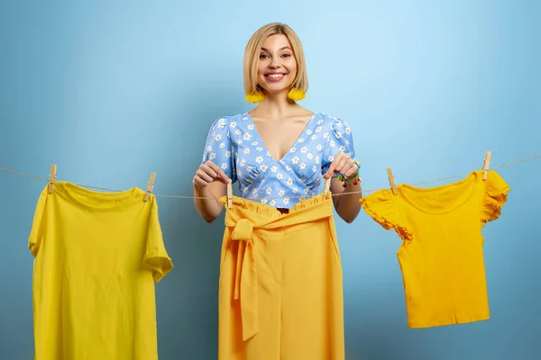 Счастливая Молодая Женщина Вешает Свою Красочную Одежду Бельевую Веревку Голубом — стоковое фото