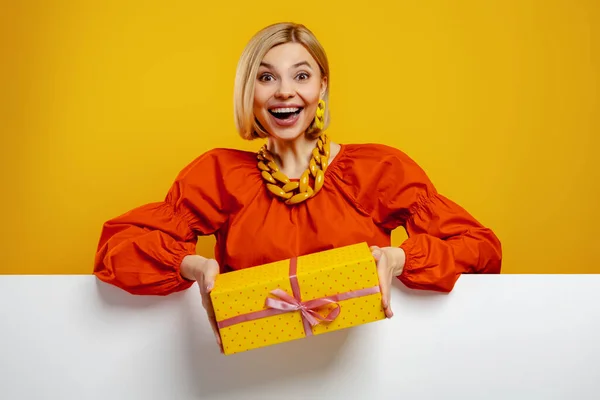 Удивлённая Молодая Женщина Держит Подарочную Коробку Улыбается Жёлтом Фоне — стоковое фото