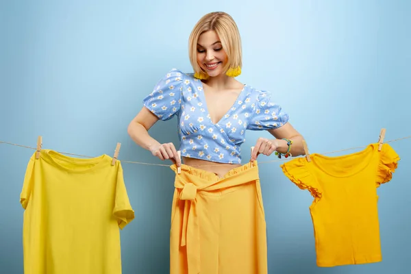 Attraente Giovane Donna Appesa Suoi Vestiti Colorati Clothesline Contro Sfondo — Foto Stock