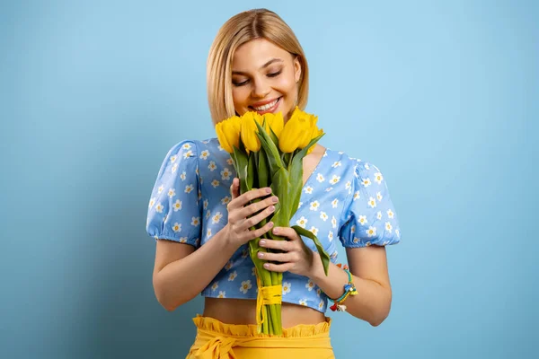Счастливая Молодая Женщина Наслаждается Ароматом Свежих Тюльпанов Голубом Фоне — стоковое фото